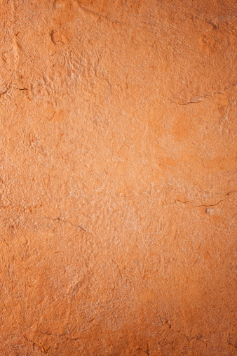 Old terracotta painted stucco wall with cracked plaster. Background texture.