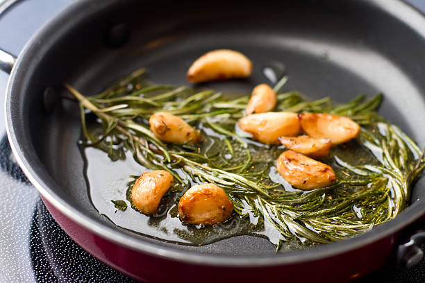 sauté di germogli di aglio e rosmarino, olio d'oliva - rosemary food herb cooking foto e immagini stock