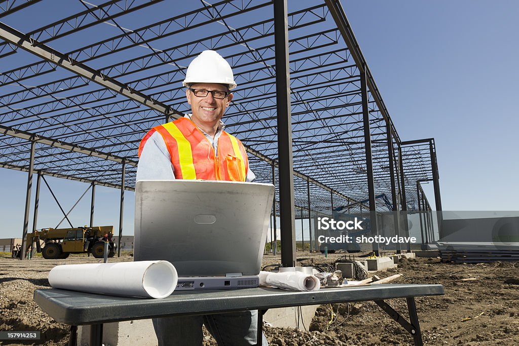 Engineer and Plans An engineer with blueprints and a laptop computer at a construction site. Web Page Stock Photo