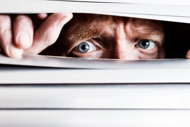 istock Sad, worried man's eye peeps through blinds despairingly 157914476