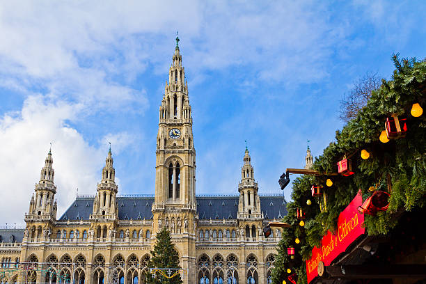 Hanging Christmas decorations in front of the Vienna Rathausplatz where every year a big Christkindlmarkt is held, the most important Christmas market among the numerous of the city. In the background stands the imposing Vienna City Hall, a beautiful example of Gothic Revival architecture. Wien, Austria.