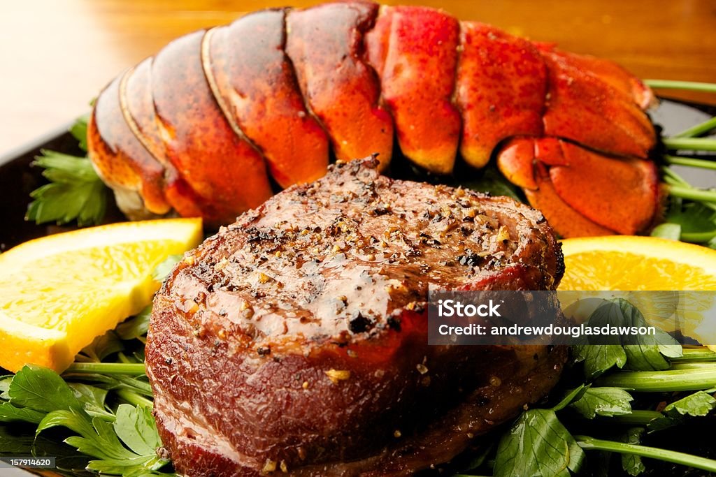 Steak &amp; Lobster Close up shot a filet mignon with lobster tail. They are set on a bed of parsley with oranges. Lobster - Seafood Stock Photo