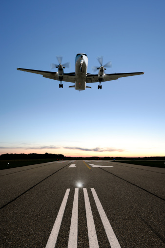 twin propeller airplane landing on runway at twilight, vertical frame (XXXL)