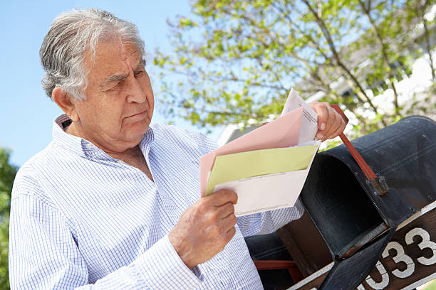 preocupado senior hispânico homem verificação de caixa de correio - looking into mailbox imagens e fotografias de stock