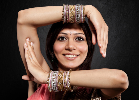 A young woman dressed in a traditional Indian sari, dancing against a black background.