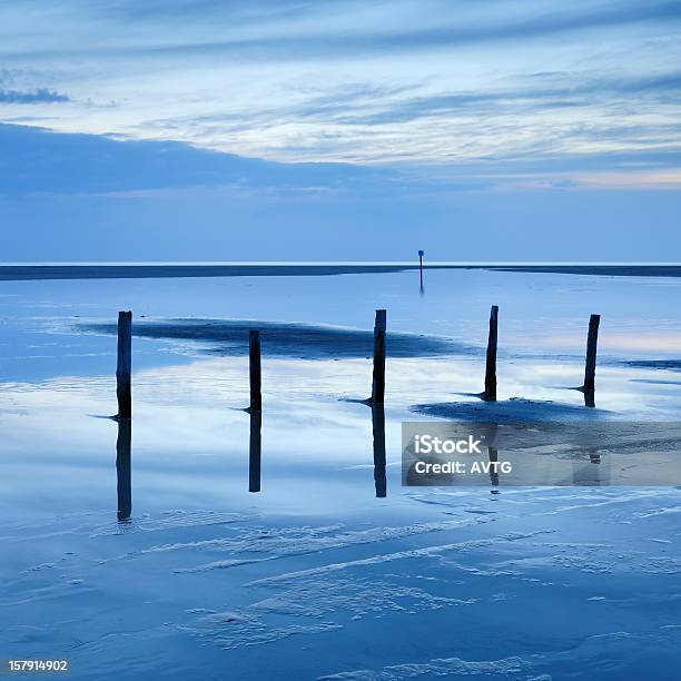 Low Tide Seascape With Wooden Posts In Tidal Pool Stock Photo - Download Image Now - Beach, German North Sea Region, Loneliness