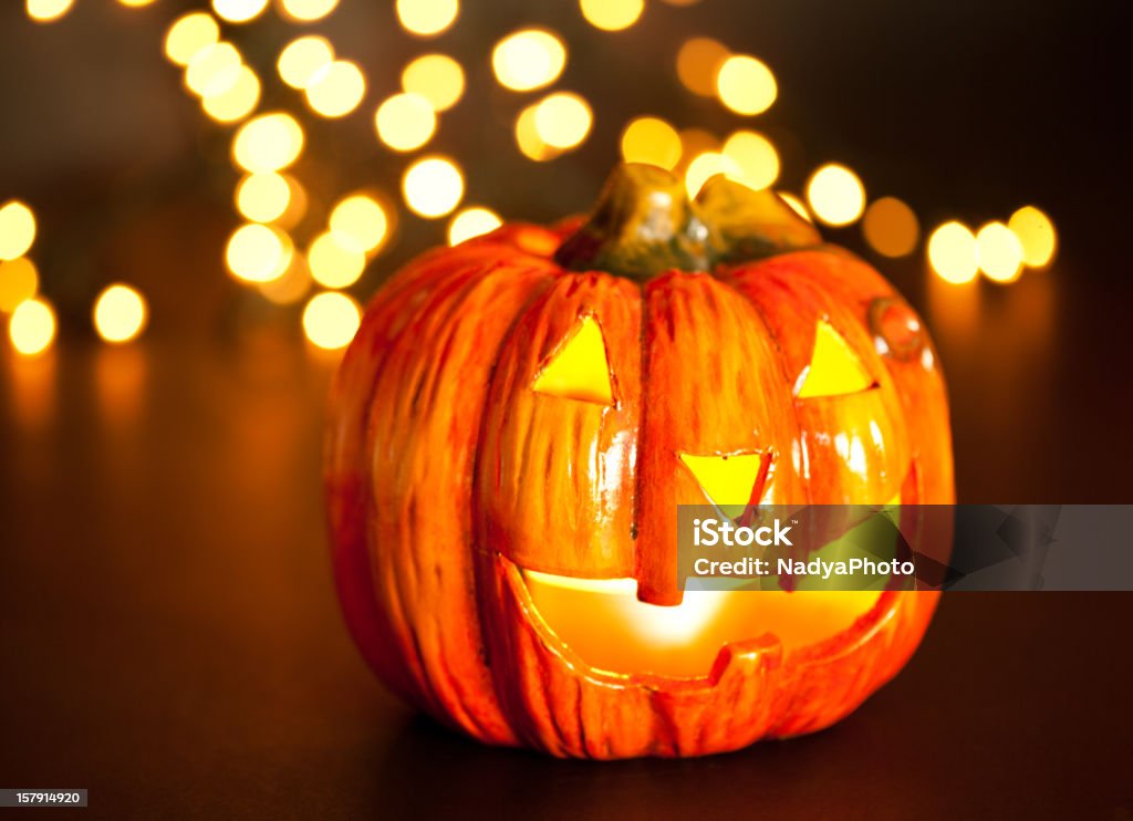 Halloween Halloween pumpkin head with beautiful bokeh lights in the background, scary smile. Light inside. American Culture Stock Photo