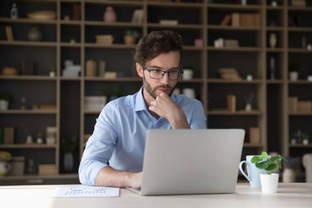 istock Focused young businessman working at laptop computer 1579155267