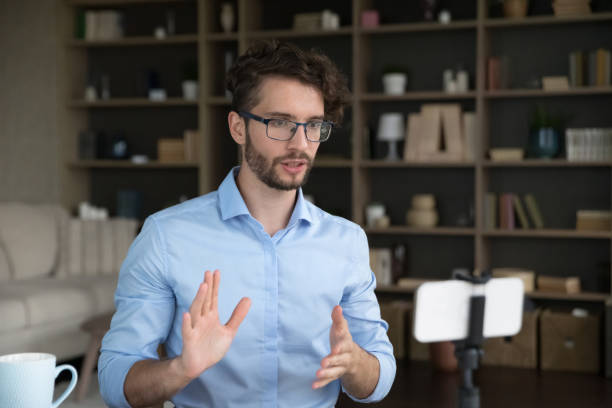 istock Handsome young business influencer in stylish eyeglasses streaming on Internet 1579155792