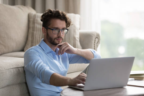 istock Serious freelancer man in stylish glasses working at laptop 1579155798