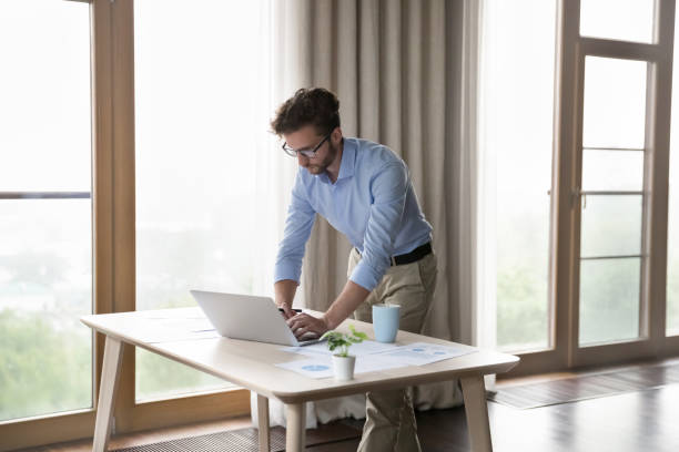 istock Serious young small business owner man working at laptop 1579155890