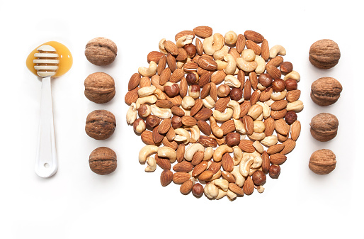 isolated almonds, cashew, hazelnut walnut and spoon with honey