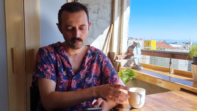 Man with coffee sunny balcony