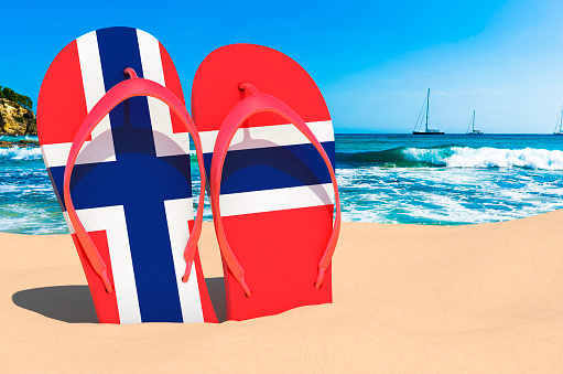 Flip flops with Norwegian flag on the beach. Norway resorts, vacation, tours, travel packages concept. 3D rendering