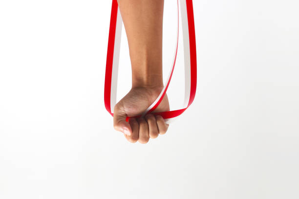 A man with a fist holding a red and white ribbon with empty copy space isolated on a white background, representing Indonesia Independence Day concept