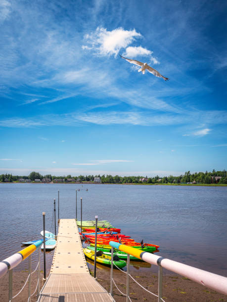 With their bright red, yellow and blue colors standing out against the background,  two kayaks are stored on a scaffold attached to a dock on Little Traverse Bay, Michigan, USA. With their paddles nearby , the boats can  be used for summer extreme water sport as well as rest, leisure, adventure and entertainment on the Lake Michigan bay.