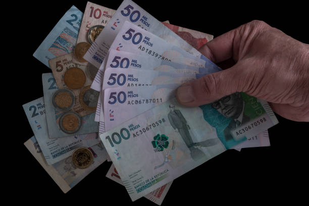 рука мужчины с монетами и банкнотами - колумбийского происхождения стоковые фото и изображения
