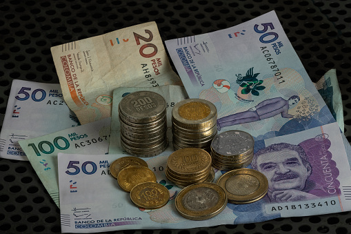 Large stack of international coins against a grey background.