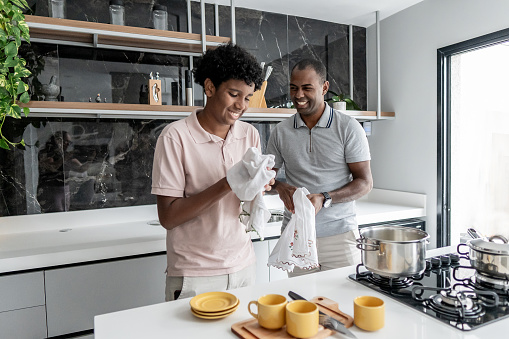 Father and son washing dishes, cups and cutlery