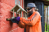 Man with beard building a birdhouse at the backyard.