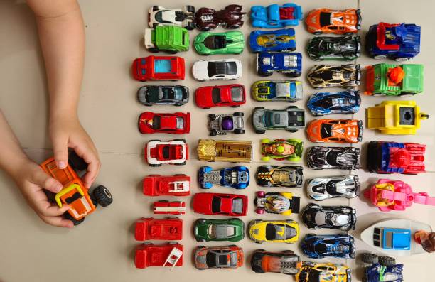 Child playing with toys Child's hands holding a toy. Toy cars in a row. Child playing. Colourful cars. toy vehicle stock pictures, royalty-free photos & images