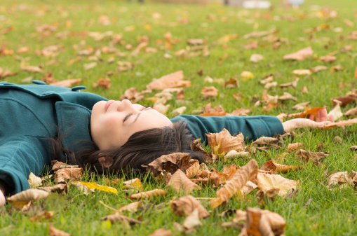 Young Asian woman lying down on Autumn grass.