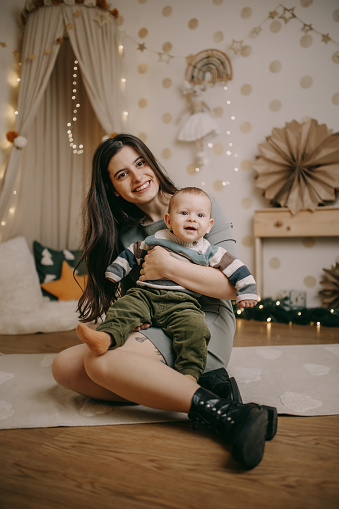 Portrait of happy young mother with baby boy in Christmas atmosphere.
