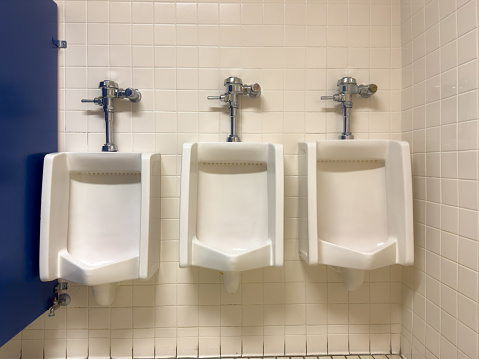 three (3) white urinals in a men's bathroom