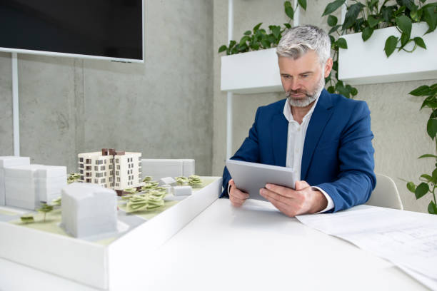 istock Architects or engineer working with blueprint and house model in the office. 1579616422