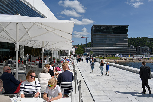 Oslo, Norway, July 5, 2023 - Terrace of the Opera House Restaurant (Restauranthuset Operaen) in Oslo with the Edvard Munch Museum in the background.