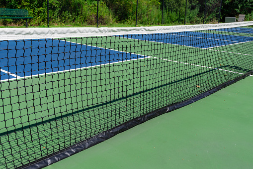 Example image of an empty pickleball court with multi-color surface and white lines.