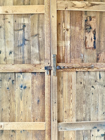 Vertical close up of the knots in timber of an old wooden farm barn door with latch in country rural Australia
