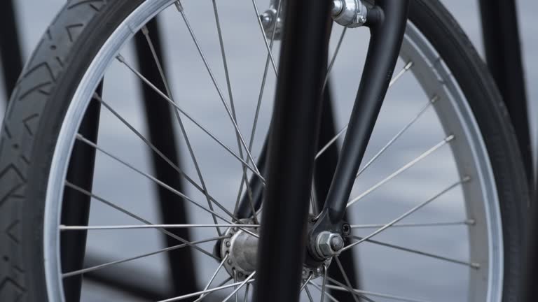 Closeup front bicycle wheel standing on shared parking. Alternative transport.