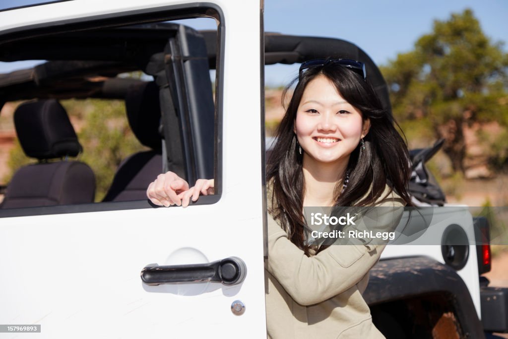 Giovane donna in piedi sulla strada di un veicolo - Foto stock royalty-free di Fuoristrada