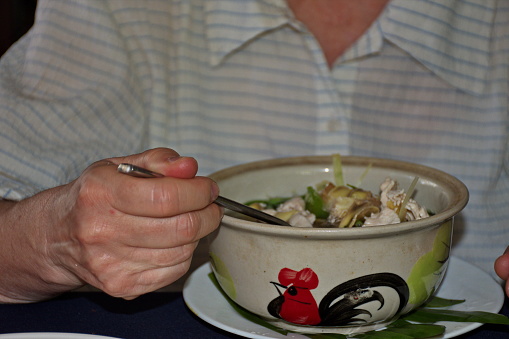 Midsection of woman eating soup from painted bowl