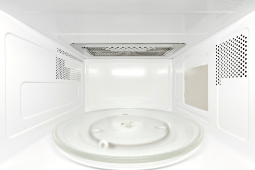 Frontal view inside white, empty clean microwave oven interior