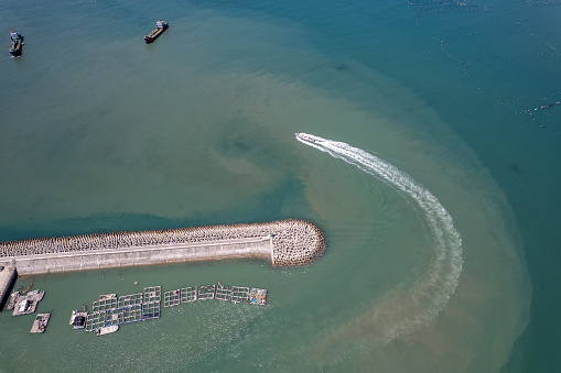 Vertical aerial view of a fishing boat departing from the fishing village