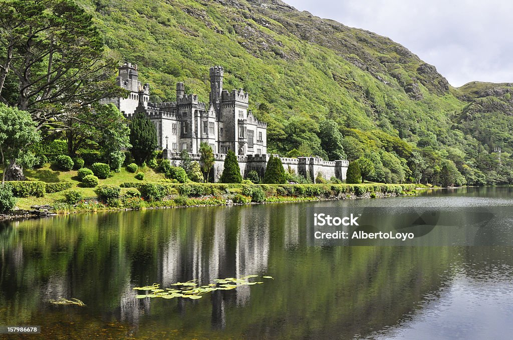 View from water of Kylemore Abbey near trees in Ireland 	Kylemore Abbey in Connemara mountains, Ireland Castle Stock Photo