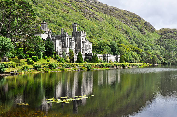 View from water of Kylemore Abbey near trees in Ireland 	Kylemore Abbey in Connemara mountains, Ireland irish culture stock pictures, royalty-free photos & images
