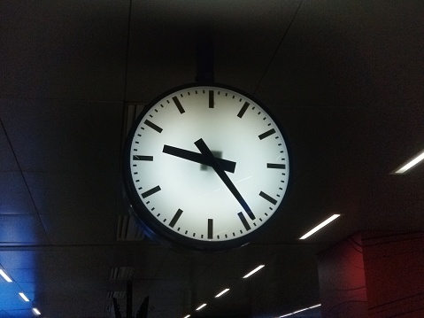 Standard black office clock on black smokey background