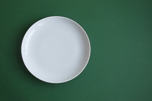 Above shot of white plate on green background