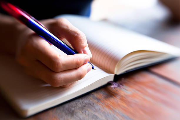 istock Close-up of hand pen writes in a notebook 157995067