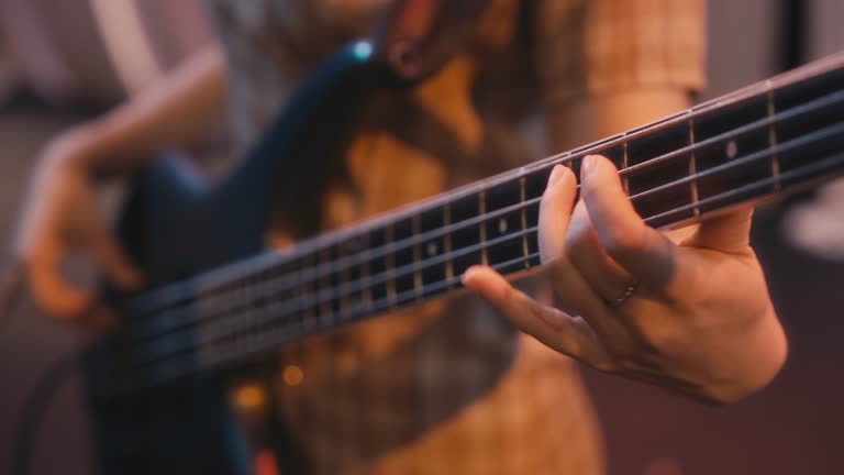 Close up Japanese female bass guitarist plucking enjoying with Young Asian Multiracial group live band