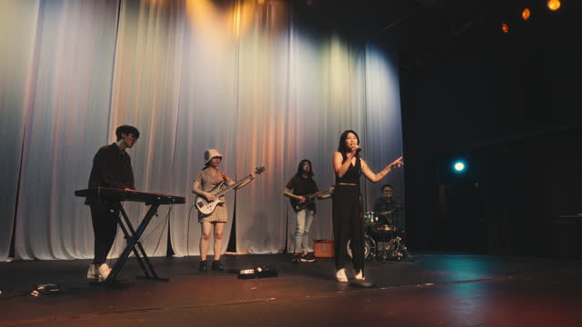 Chinese female pop lead singer singing together with Multiracial group live band performance on stage