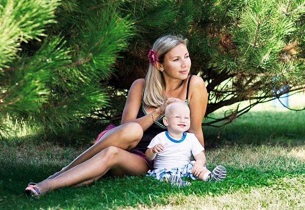 Schöne Frau mit einem Kind sitzt auf dem Rasen – Foto