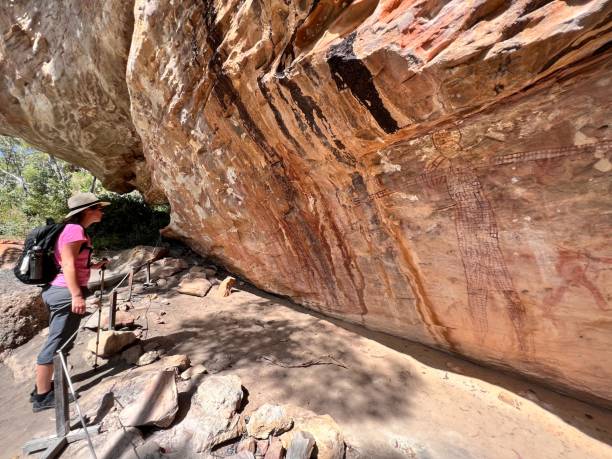 donna australiana guarda la pittura di arte rupestre indigena australiana penisola di cape york queensland australia - aboriginal rock art foto e immagini stock