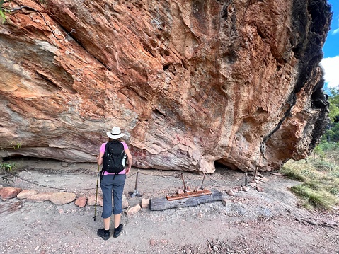 Cape York - June 21 2023:Australian woman look at Indigenous Australian rock art painting on Split Rock in Cape York Queensland, Australia. Rock art is an integral part of First Nations life and customs