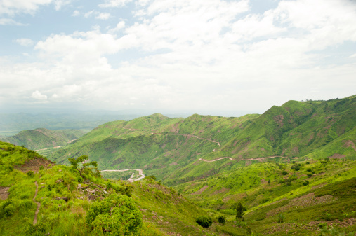 The green mountains of Burundi in Central Africa with a mountain road (connects the capital Bujumbura with South Kivu in DR Congo) and on leat side of the image with the Ruzizi River, 