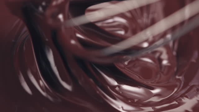 Slow motion of mixing melted premium dark chocolate with a whisk