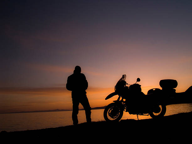 standing motorrad fahrer-silhouette auf den sonnenuntergang - lake tranquil scene landscape zen like stock-fotos und bilder